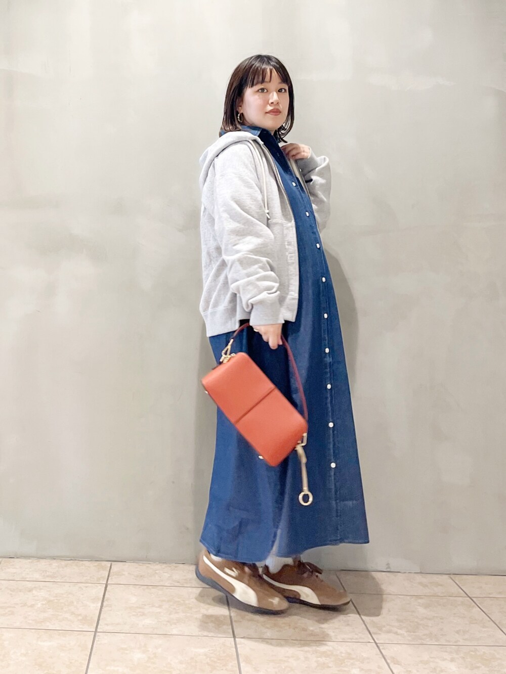 ブルー系のワンピース、オレンジ系のショルダーバッグ、ブラック系のスニーカーを着用したレディースの秋コーディネートの7枚目の写真