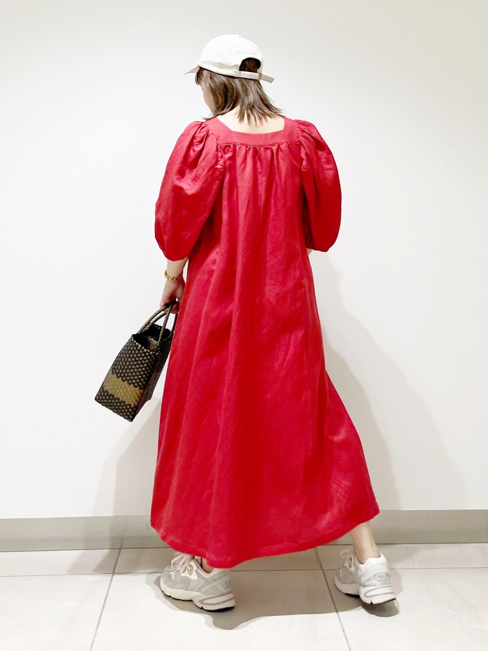 レッド系のワンピース、ホワイト系のスニーカー、ブラック系のトートバッグを着用したレディースの夏コーディネートの5枚目の写真