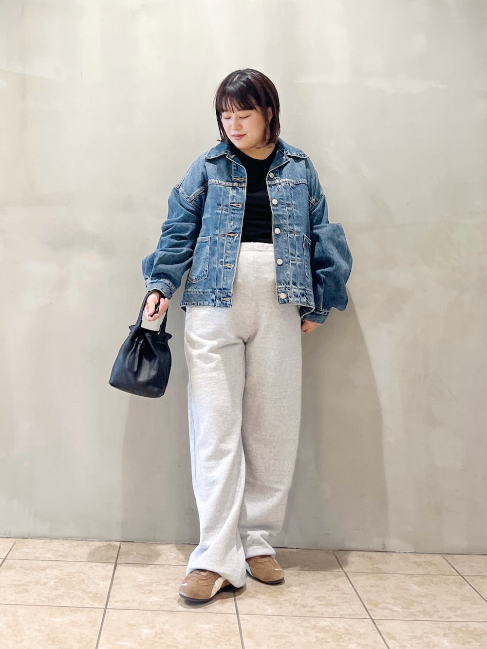 ブルー系のデニムジャケット、ブラック系のスニーカー、グレー系のその他パンツを着用したレディースの秋コーディネートの5枚目の写真