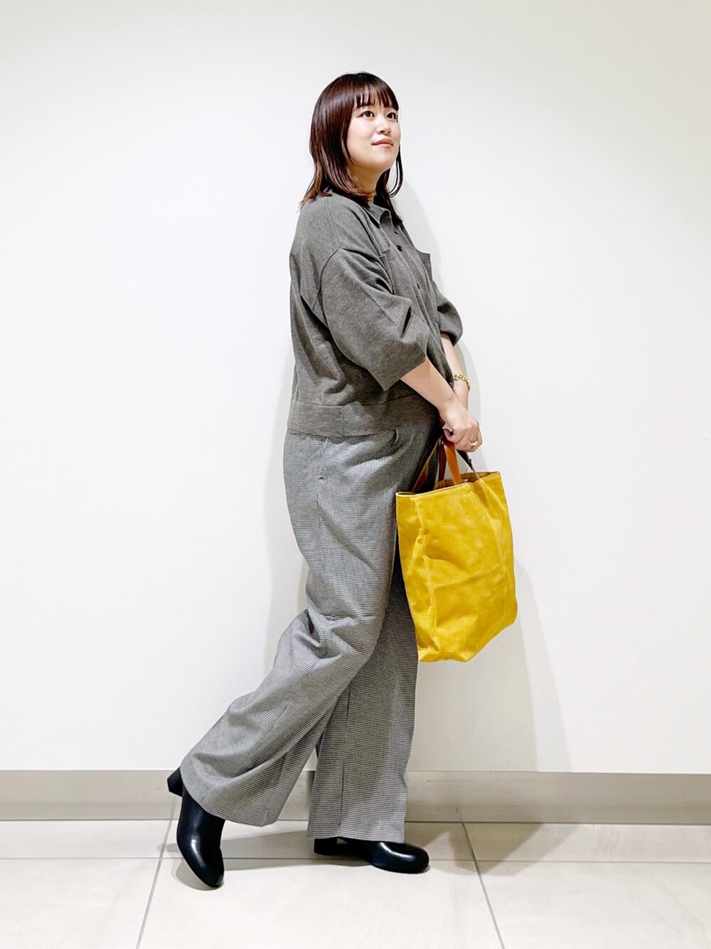 グレー系のニット/セーター、ベージュ系のパンツ、イエロー系のトートバッグを着用したレディースの秋コーディネートの10枚目の写真