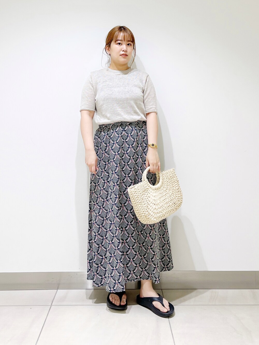 グリーン系のスカート、ベージュ系のTシャツ/カットソー、ホワイト系のハンドバッグを着用したレディースの春コーディネートの2枚目の写真