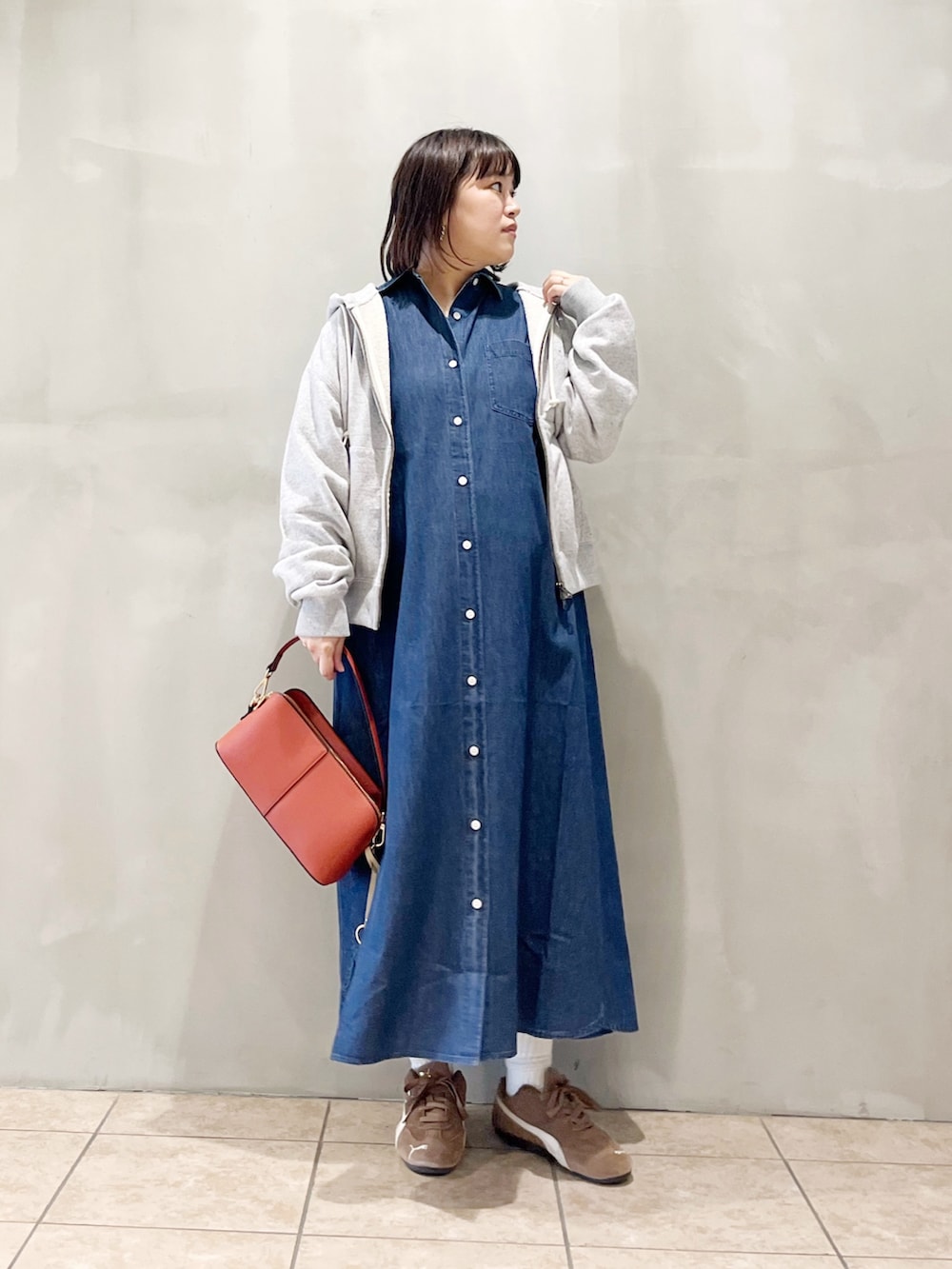 ブルー系のワンピース、オレンジ系のショルダーバッグ、ブラック系のスニーカーを着用したレディースの秋コーディネートの2枚目の写真