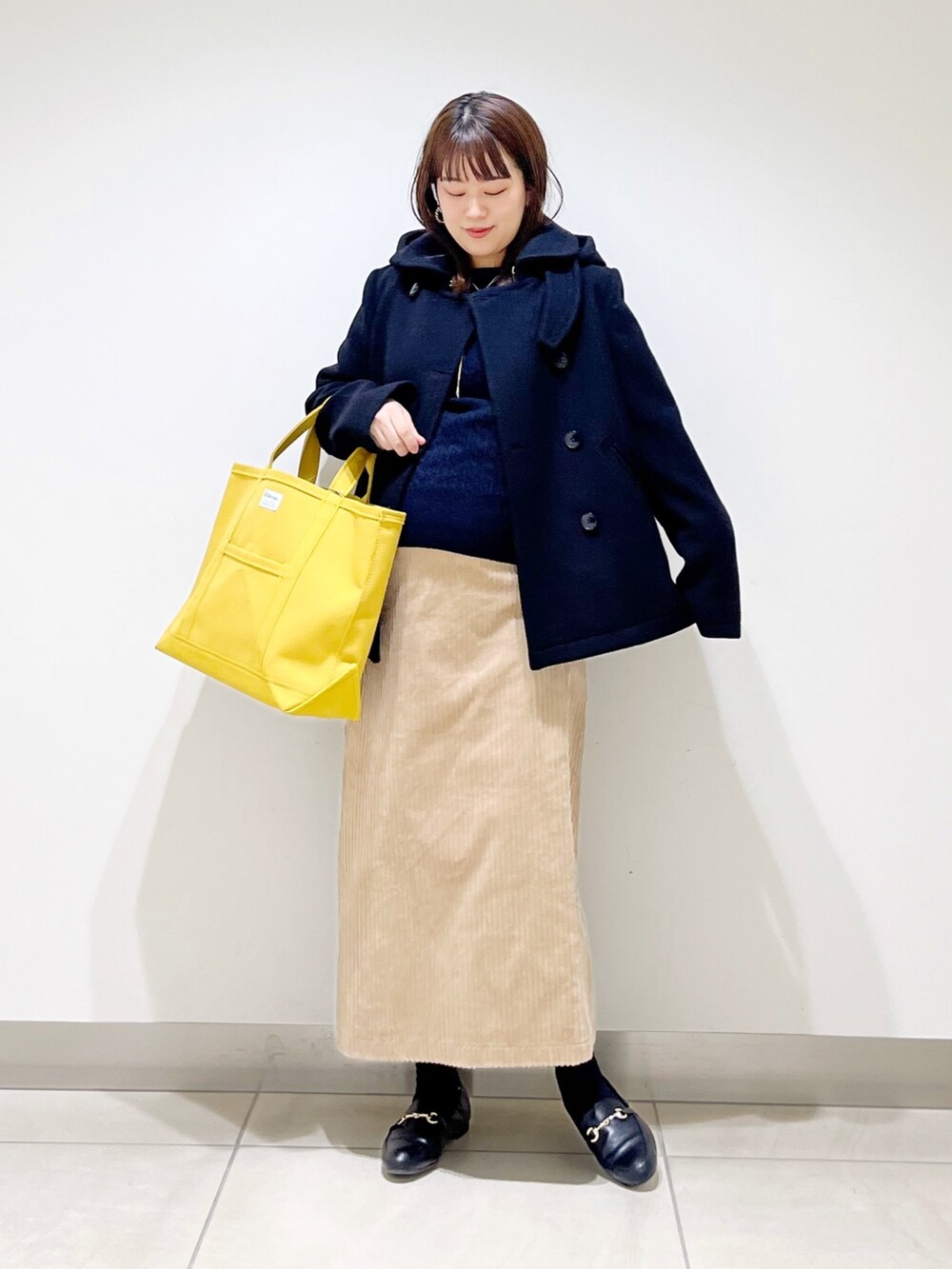 ブラック系のピーコート、ブルー系のニット/セーター、ブラック系のローファーを着用したレディースの冬コーディネートの7枚目の写真