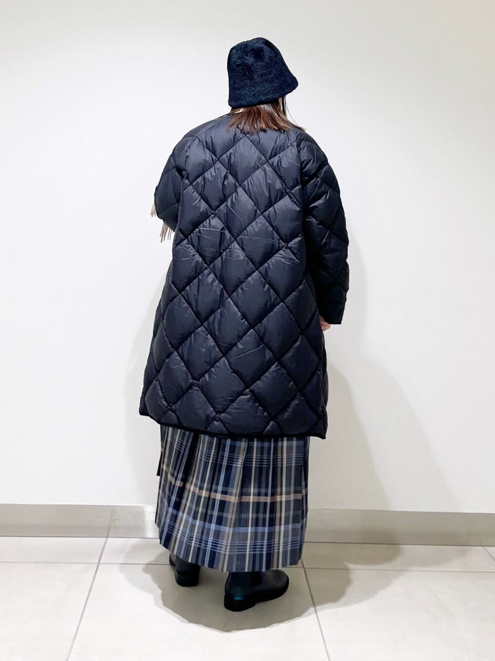 ブラック系のダウンジャケット/コート、グレー系のスカート、ホワイト系のニット/セーターを着用したレディースの冬コーディネートの7枚目の写真