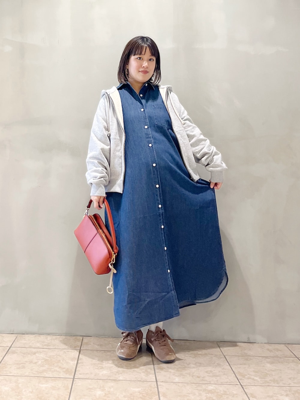 ブルー系のワンピース、オレンジ系のショルダーバッグ、ブラック系のスニーカーを着用したレディースの秋コーディネートの8枚目の写真