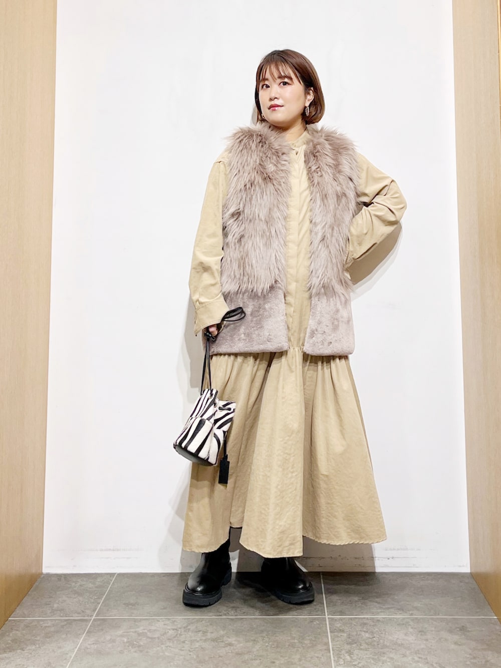 ベージュ系のベスト、ベージュ系のワンピース、その他のバッグを着用したレディースの秋コーディネートの2枚目の写真