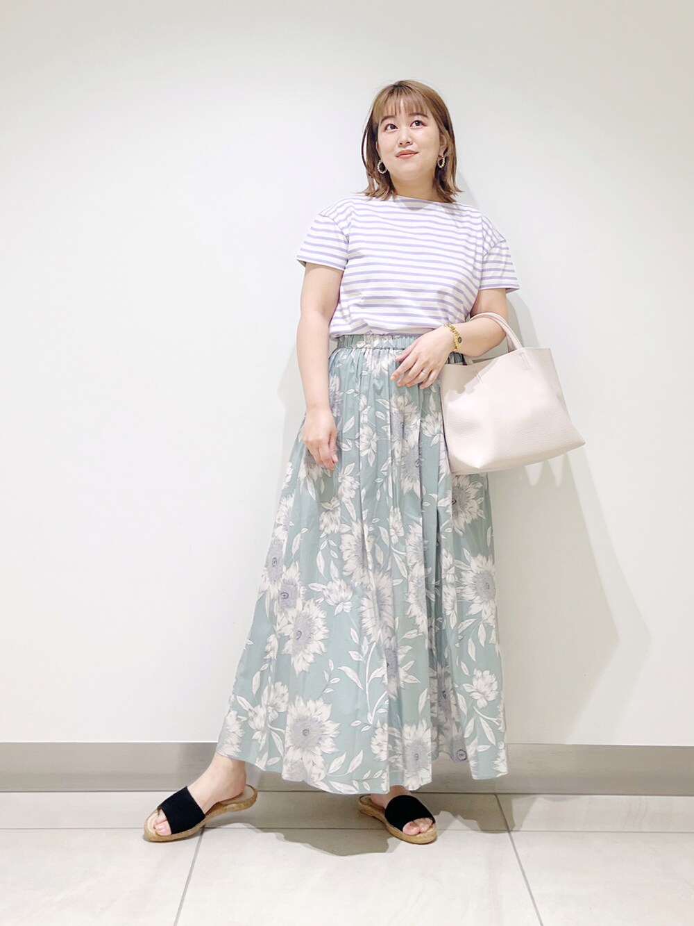 グリーン系のスカート、パープル系のTシャツ/カットソー、ホワイト系のトートバッグを着用したレディースの春コーディネートの3枚目の写真