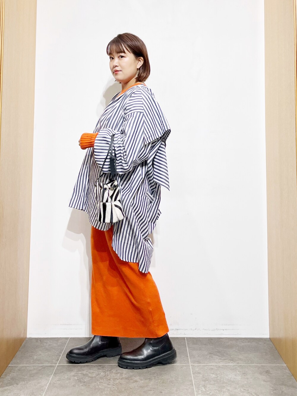 ブルー系のシャツ/ブラウス、オレンジ系のワンピース、ブラック系のブーツを着用したレディースの冬コーディネートの5枚目の写真