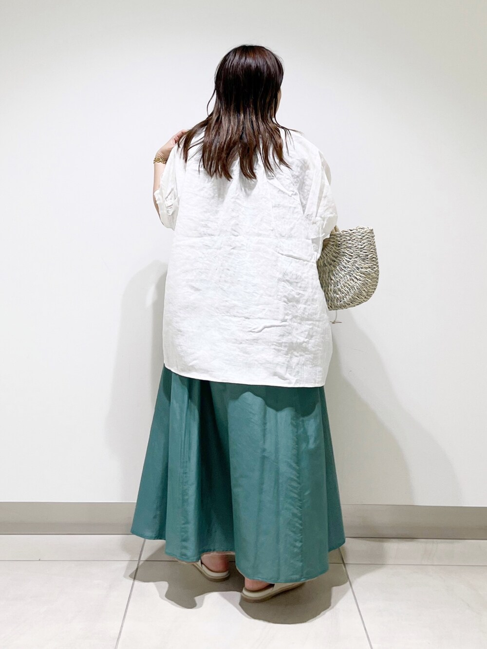 ホワイト系のシャツ/ブラウス、グリーン系のスカート、グレー系のかごバッグを着用したレディースの夏コーディネートの6枚目の写真