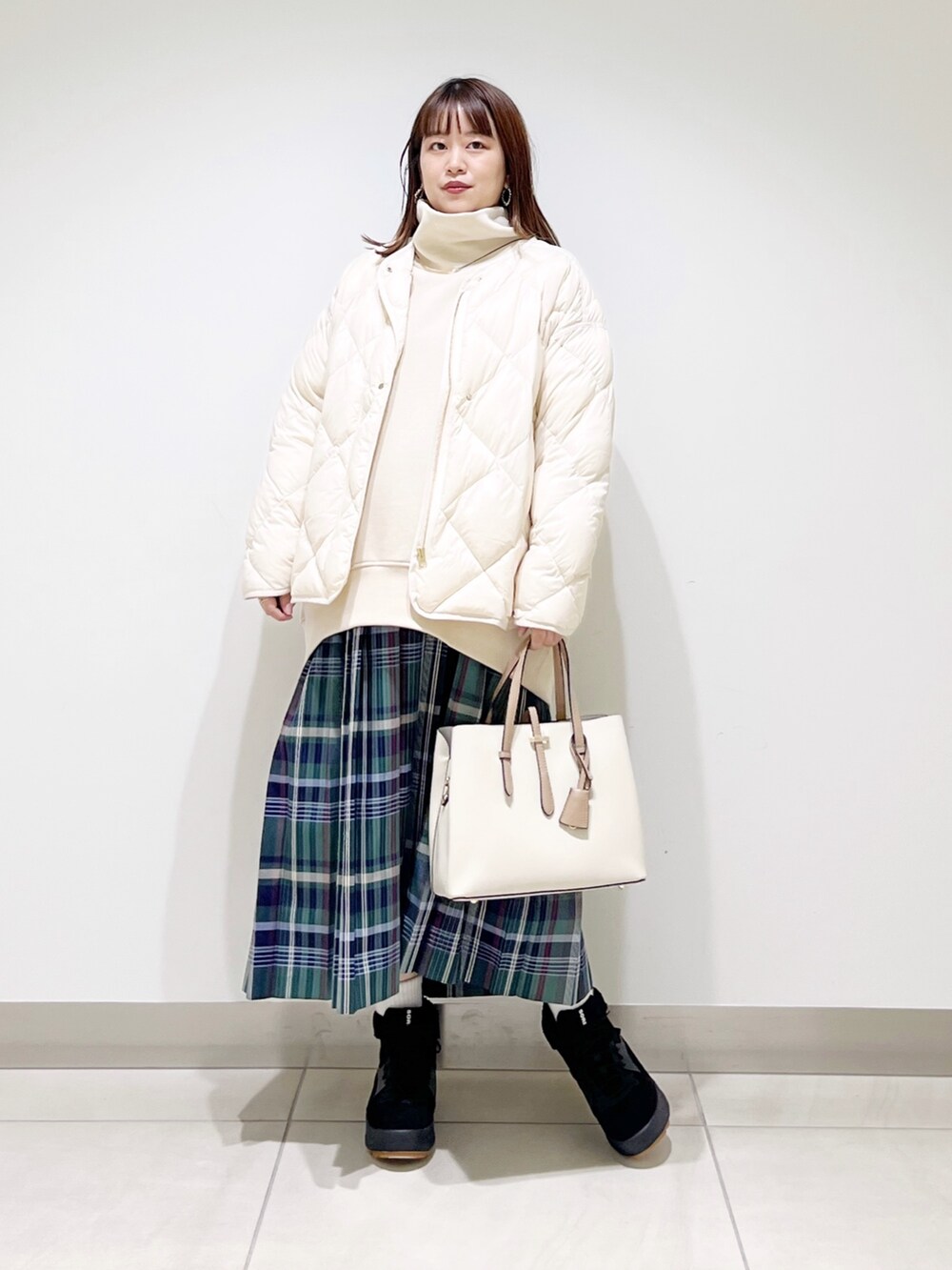 ベージュ系のスウェット、ホワイト系のダウンジャケット/コート、グリーン系のスカートを着用したレディースの秋コーディネートの9枚目の写真