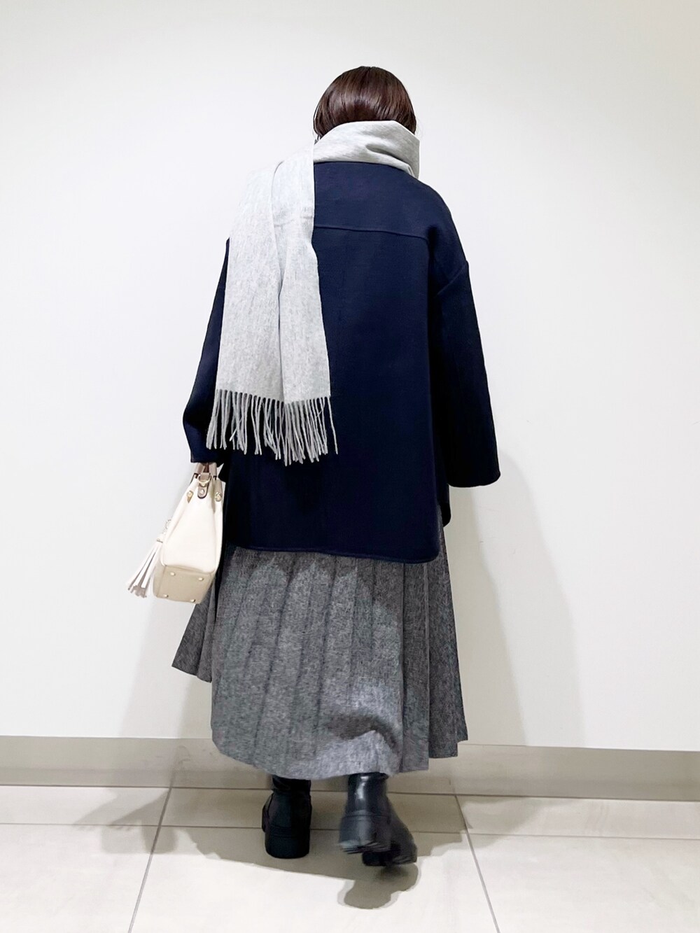 ブルー系のノーカラージャケット、グレー系のニット/セーター、ブルー系のスカートを着用したレディースの秋コーディネートの6枚目の写真