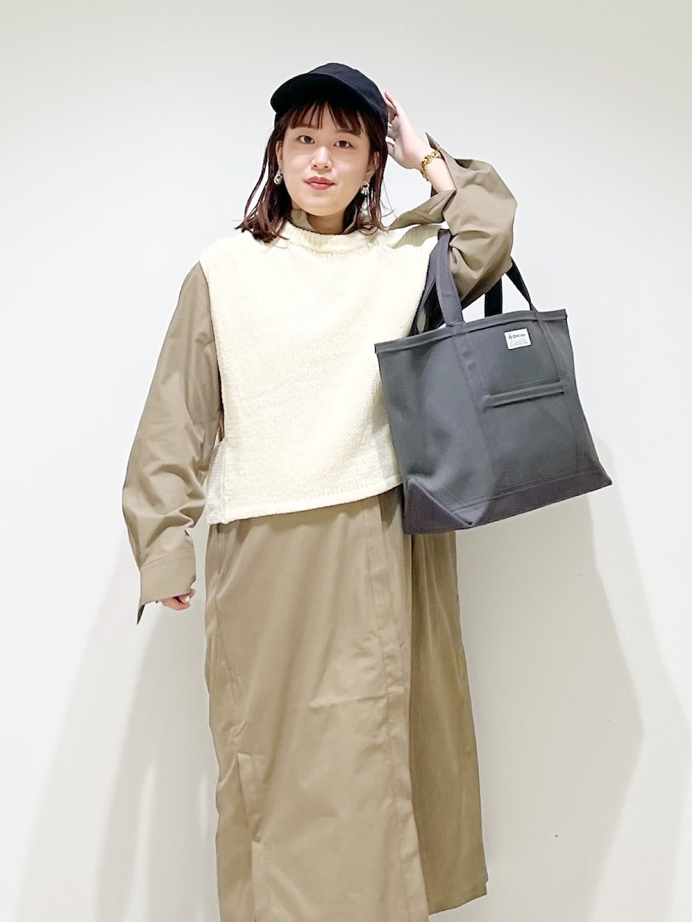 ホワイト系のベスト、グリーン系のワンピース、グレー系のトートバッグを着用したレディースの秋コーディネートの5枚目の写真