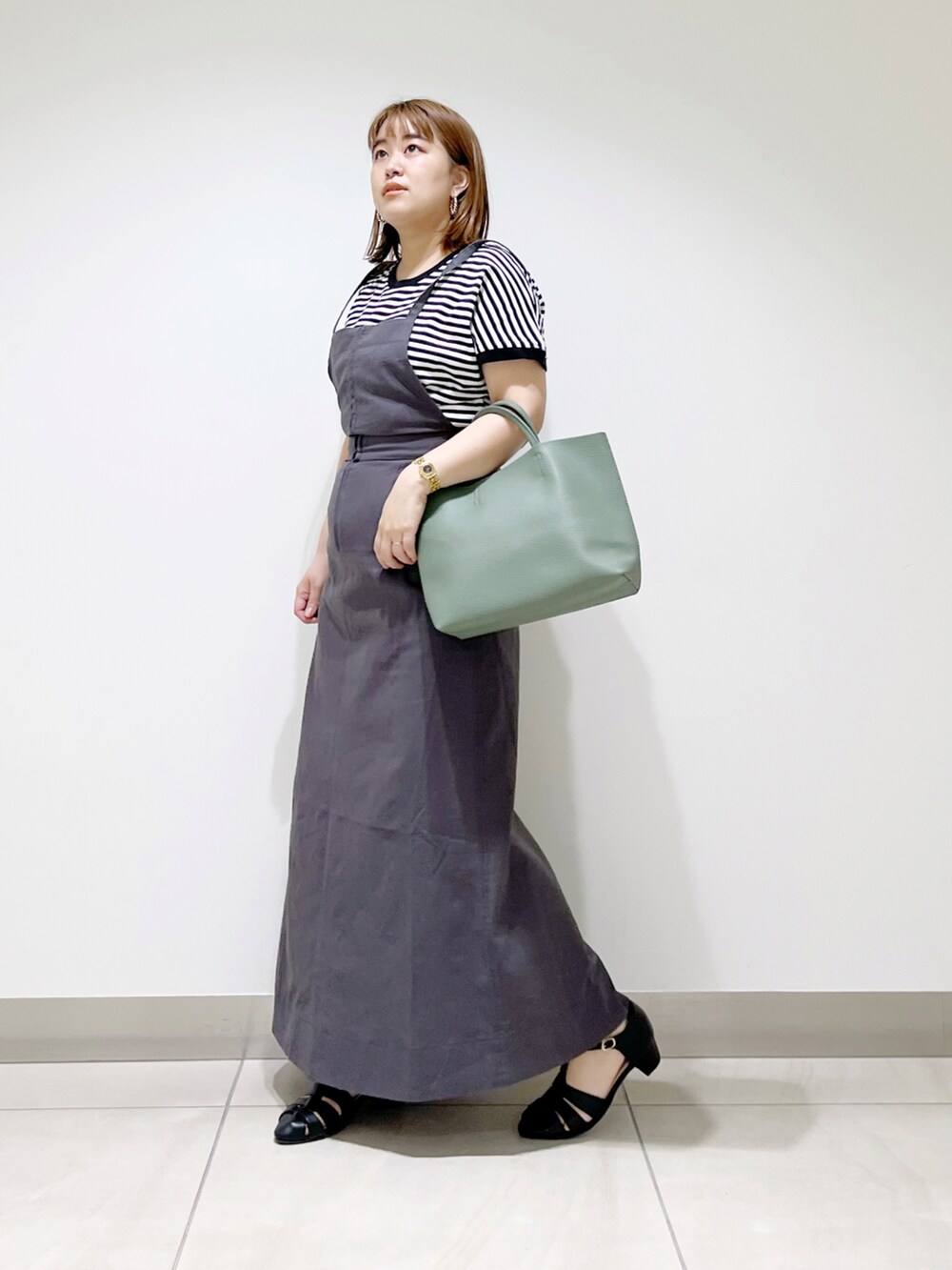 グレー系のワンピース、グリーン系のトートバッグ、ブラック系のサンダルを着用したレディースの春コーディネートの5枚目の写真