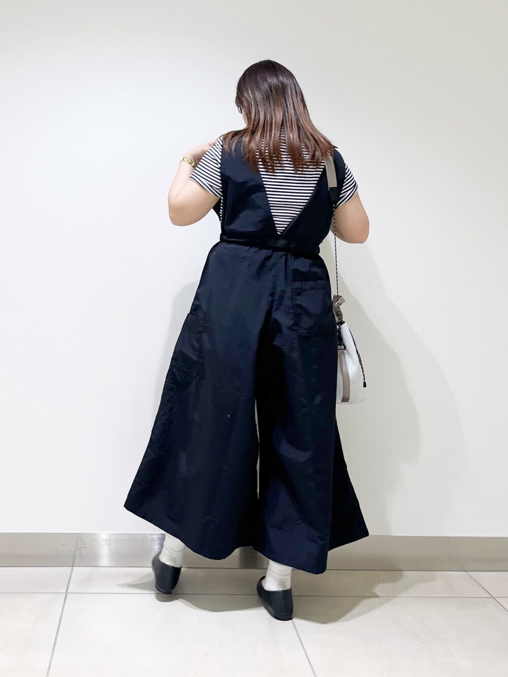 ブラック系のサロペット/オーバーオール、グレー系のTシャツ/カットソー、ホワイト系のショルダーバッグを着用したレディースの春コーディネートの4枚目の写真