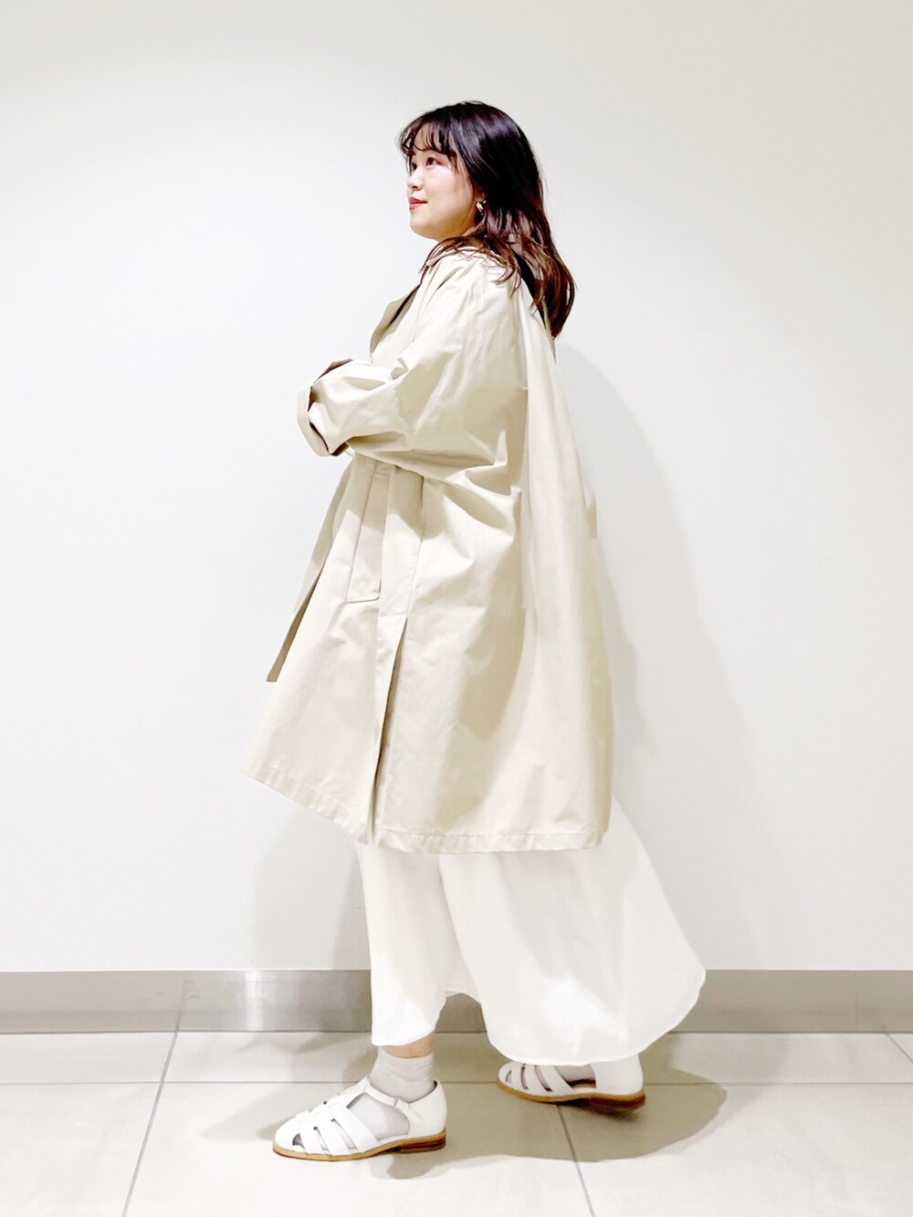 ベージュ系のポンチョ、ホワイト系のTシャツ/カットソー、ホワイト系のスカートを着用したレディースの春コーディネートの3枚目の写真