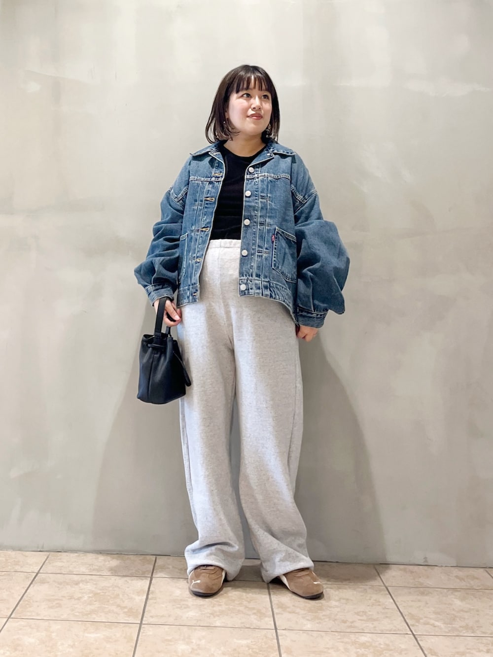 ブルー系のデニムジャケット、ブラック系のスニーカー、グレー系のその他パンツを着用したレディースの秋コーディネートの3枚目の写真