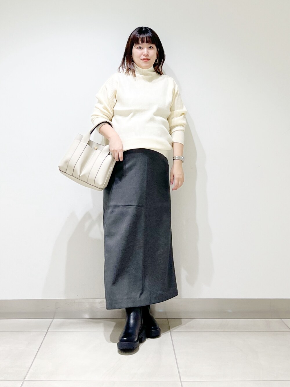 ホワイト系のニット/セーター、ホワイト系のトートバッグ、グレー系のスカートを着用したレディースの秋コーディネートの8枚目の写真