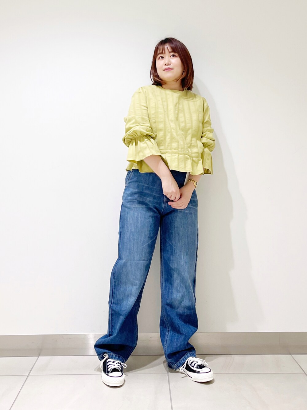 グリーン系のシャツ/ブラウス、ブルー系のデニムパンツ、ブラック系のスニーカーを着用したレディースの春コーディネートの4枚目の写真