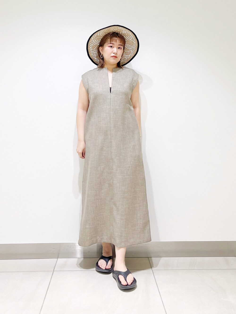 グレー系のワンピース、ブラック系のサンダル、ブラック系のハットを着用したレディースの春コーディネートの2枚目の写真