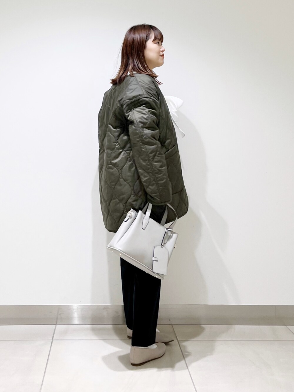 グリーン系のダウンジャケット/コート、ブルー系のパンツ、グレー系のトートバッグを着用したレディースの秋コーディネートの5枚目の写真