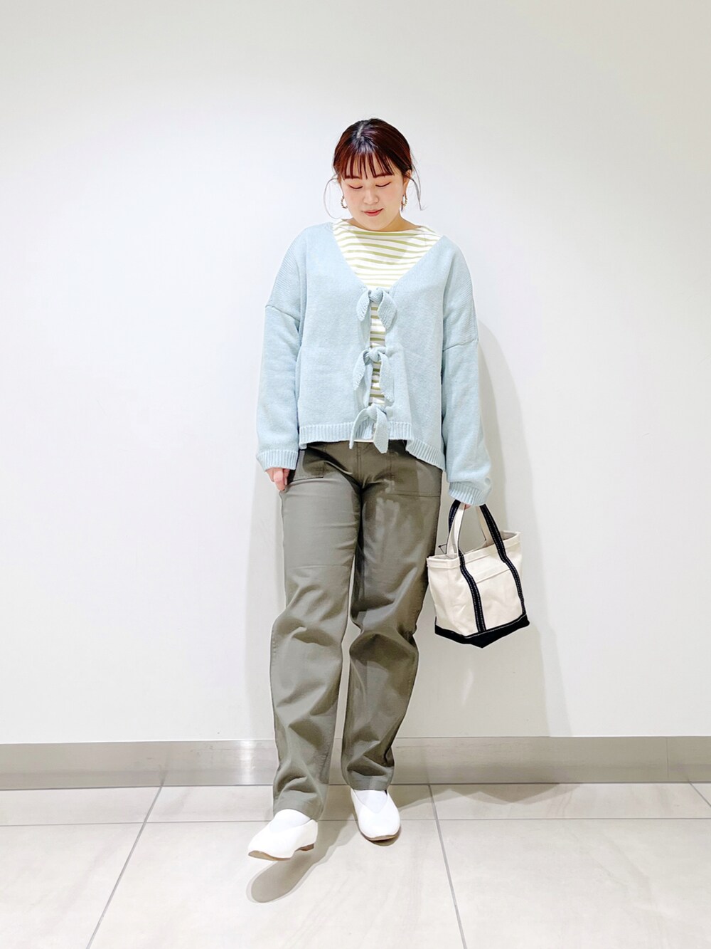 グリーン系のカーディガン/ボレロ、ブルー系のトートバッグ、ホワイト系のパンプスを着用したレディースの冬コーディネートの5枚目の写真