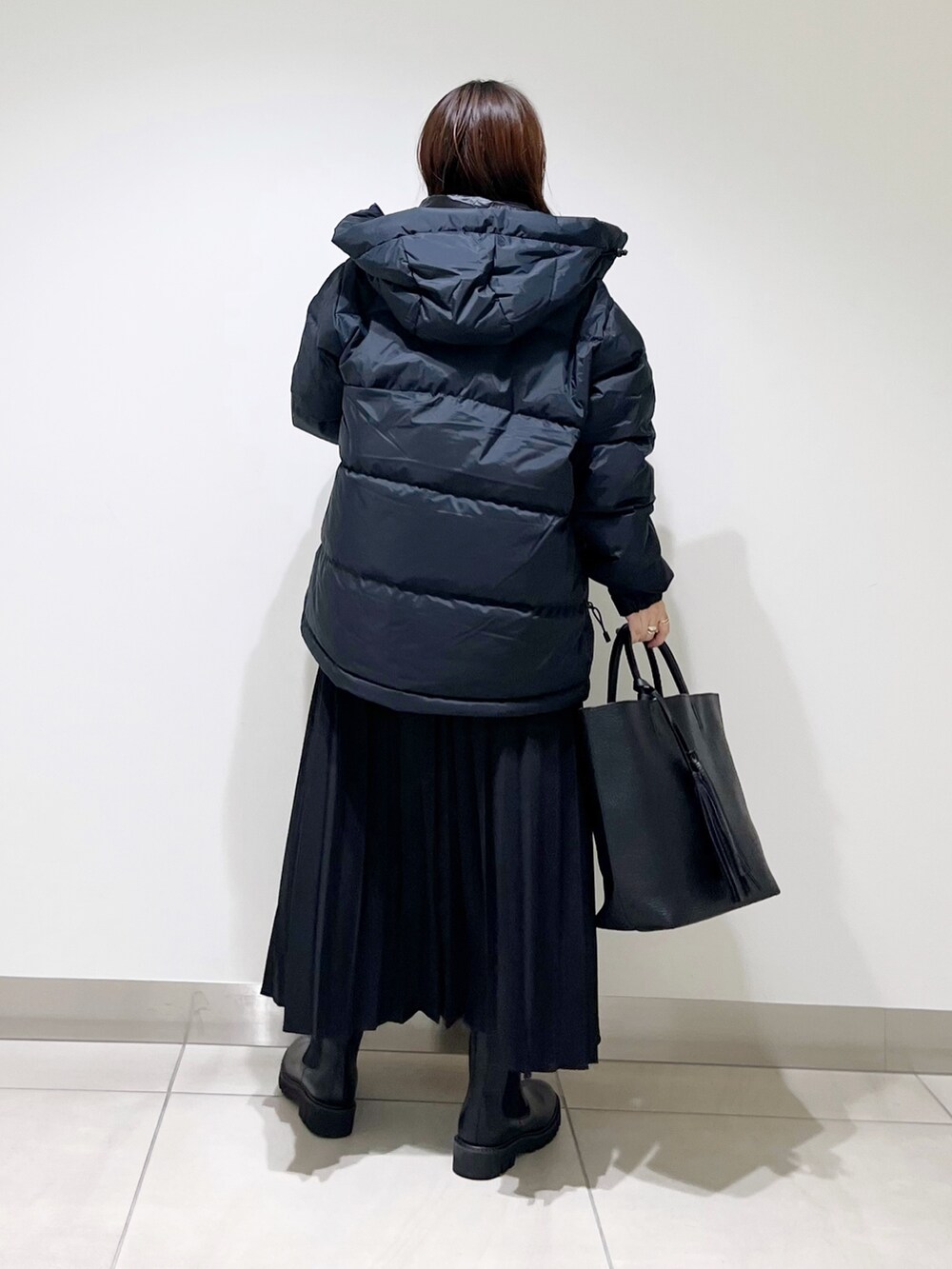 ブラック系のダウンジャケット/コート、ブルー系のTシャツ/カットソー、ブラック系のスカートを着用したレディースの秋コーディネートの6枚目の写真