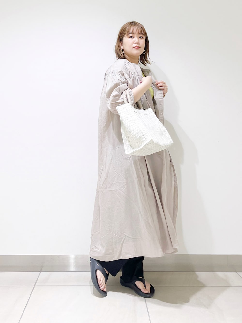 グレー系のワンピース、ホワイト系のトートバッグ、グリーン系のTシャツ/カットソーを着用したレディースの春コーディネートの2枚目の写真