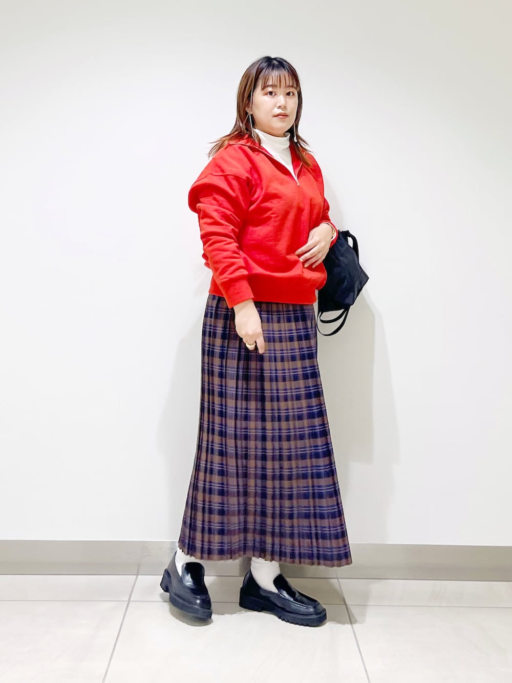 オレンジ系のスウェット、ブルー系のスカート、ブラック系のショルダーバッグを着用したレディースの秋コーディネートの2枚目の写真