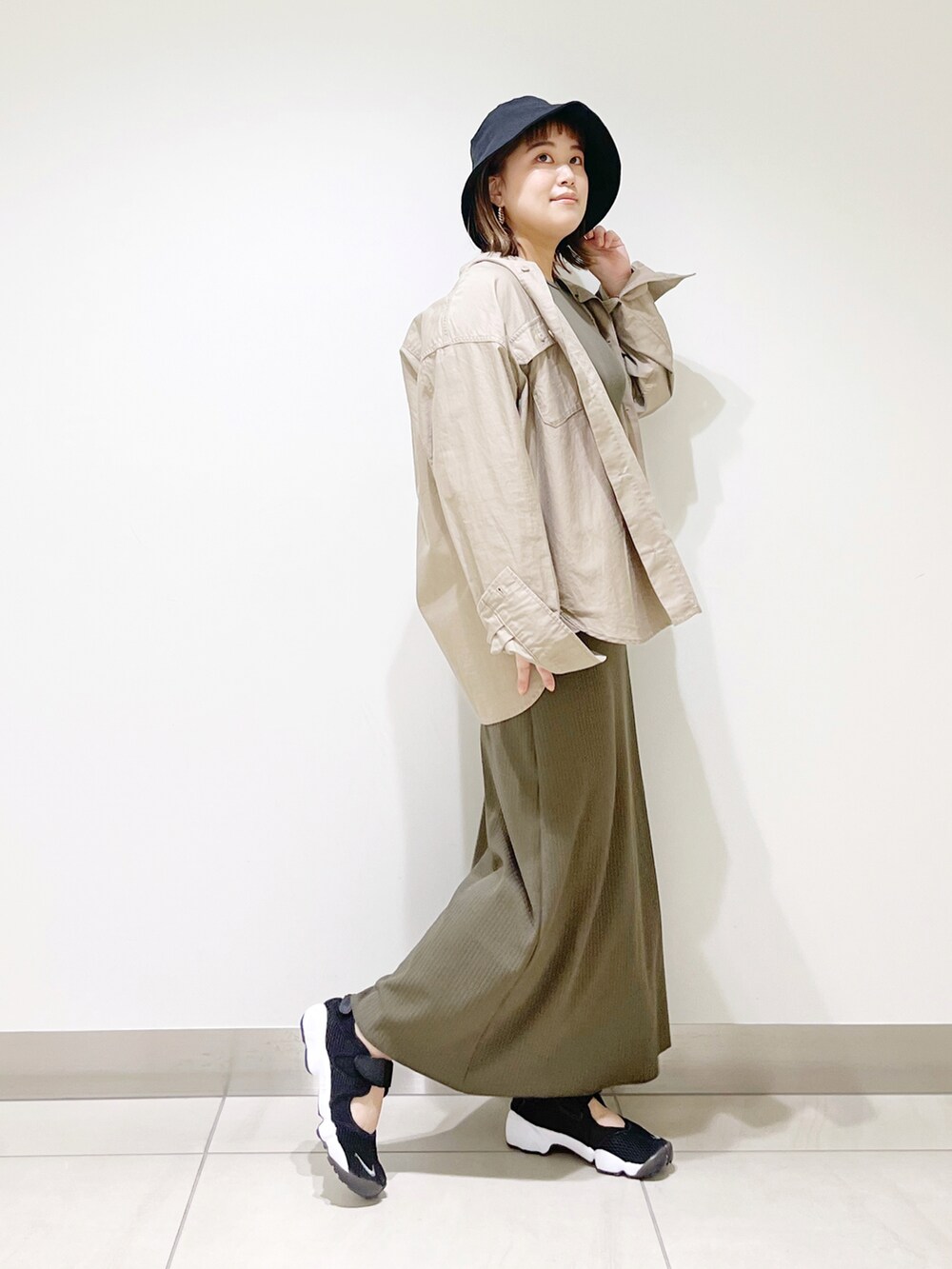 グリーン系のワンピース、ベージュ系のシャツ/ブラウス、ブラック系のスニーカーを着用したレディースの春コーディネートの3枚目の写真