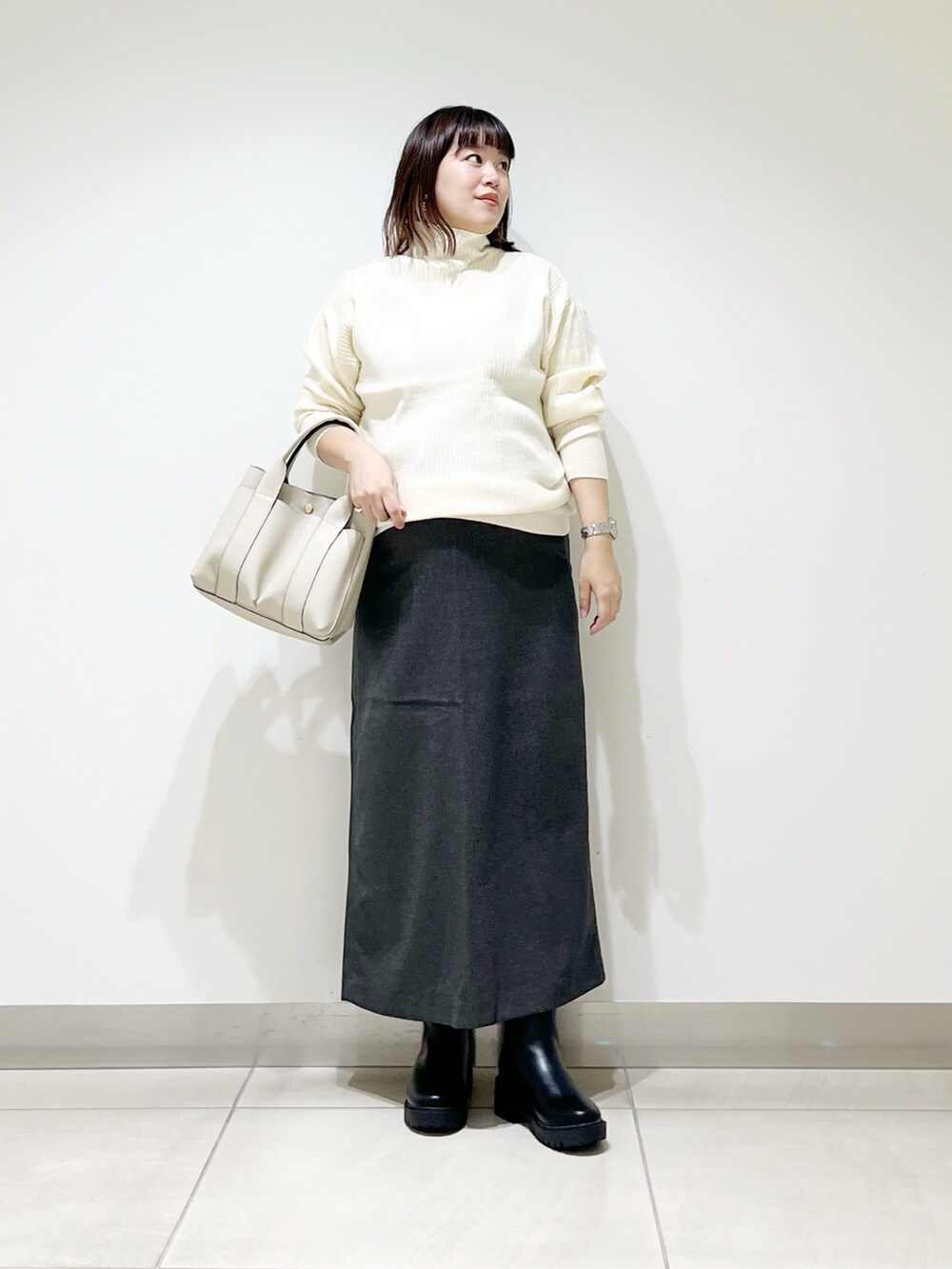 ホワイト系のニット/セーター、ホワイト系のトートバッグ、グレー系のスカートを着用したレディースの秋コーディネートの7枚目の写真