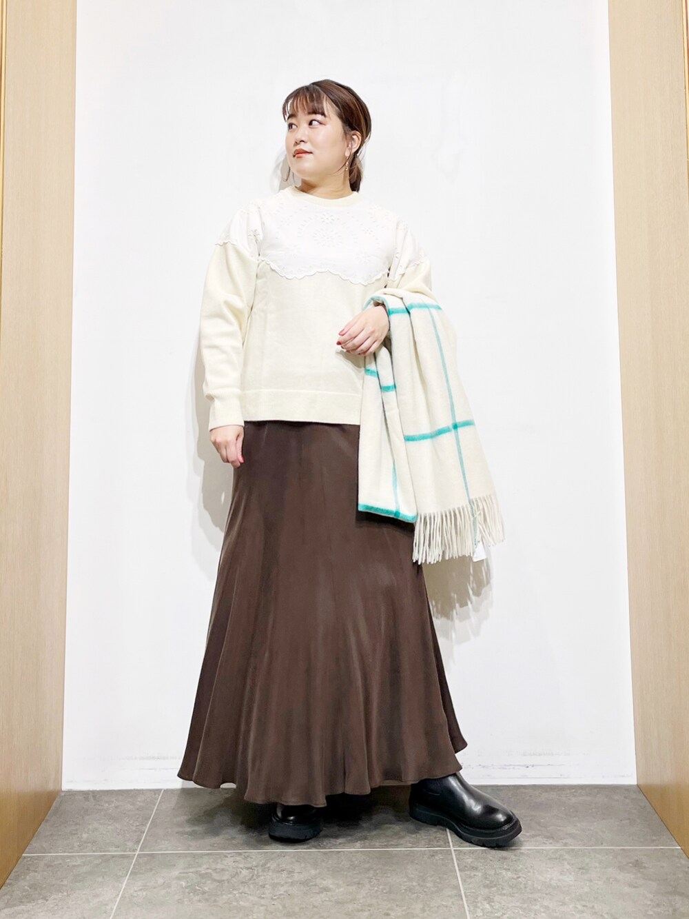 ブラウン系のスカート、ホワイト系のニット/セーター、ブラック系のブーツを着用したレディースの冬コーディネートの4枚目の写真