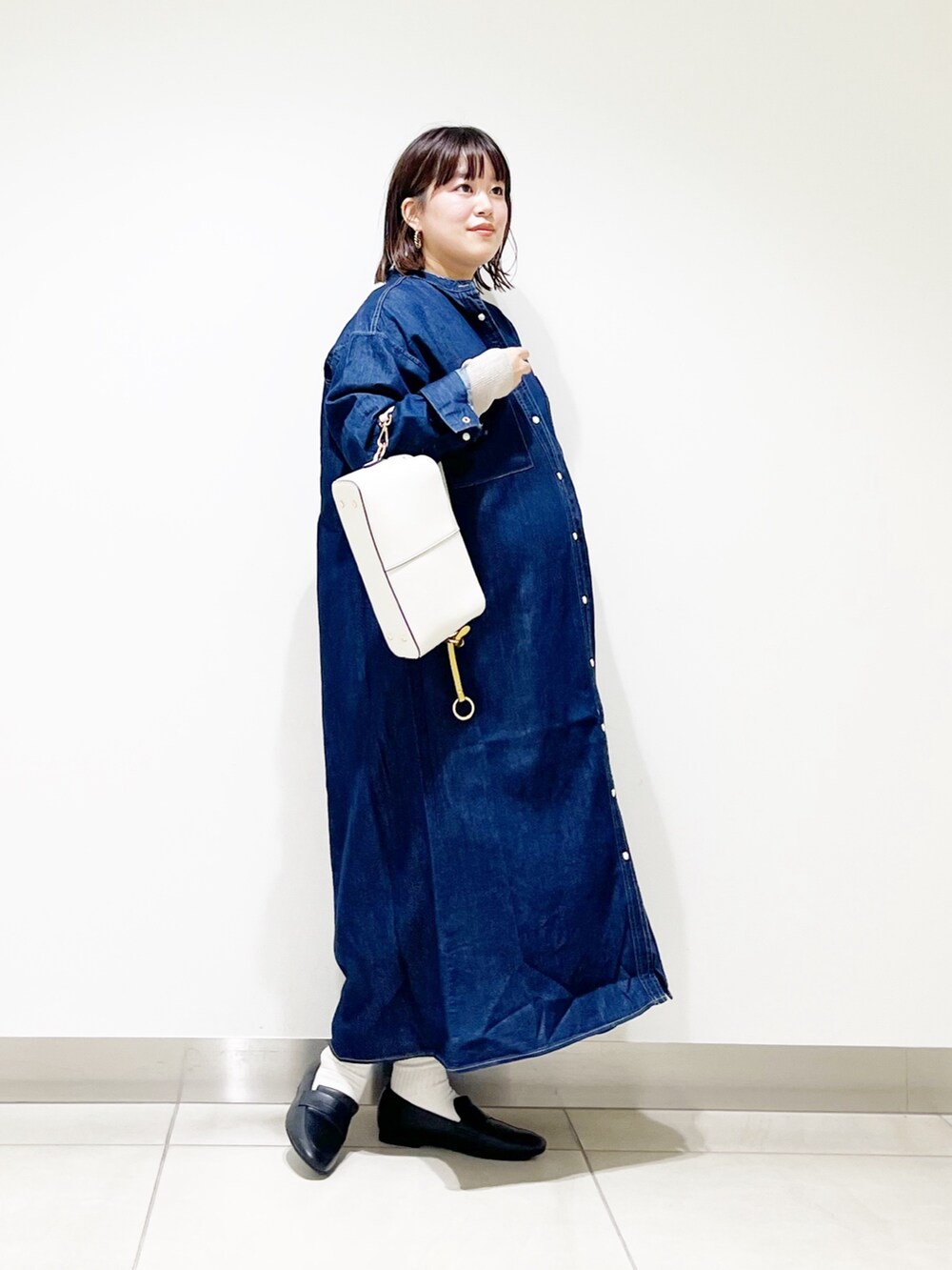 ブルー系のワンピース、ベージュ系のニット/セーター、ホワイト系のショルダーバッグを着用したレディースの秋コーディネートの6枚目の写真