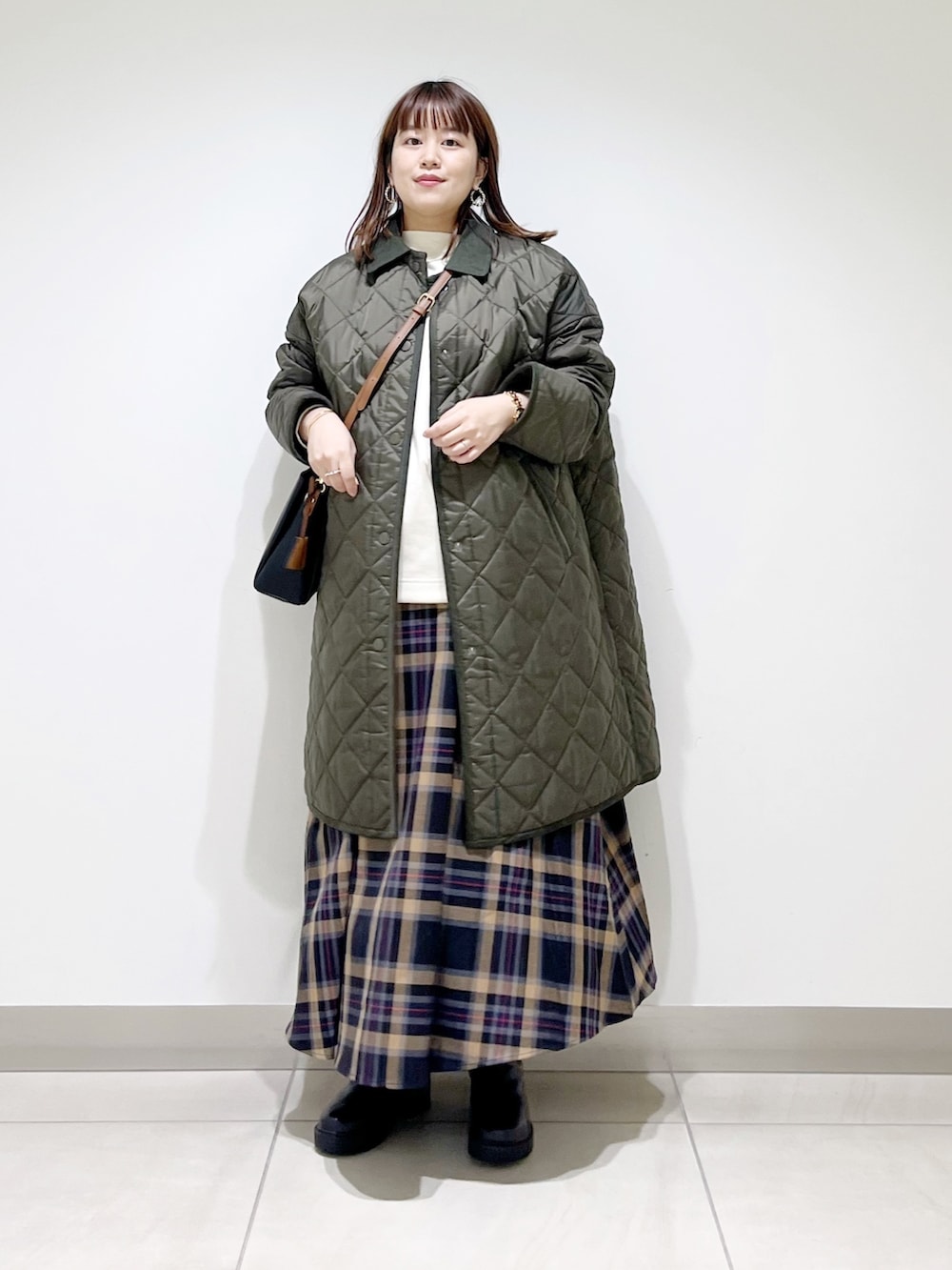 グリーン系のダウンジャケット/コート、ホワイト系のトップス、ブラウン系のスカートを着用したレディースの秋コーディネートの2枚目の写真
