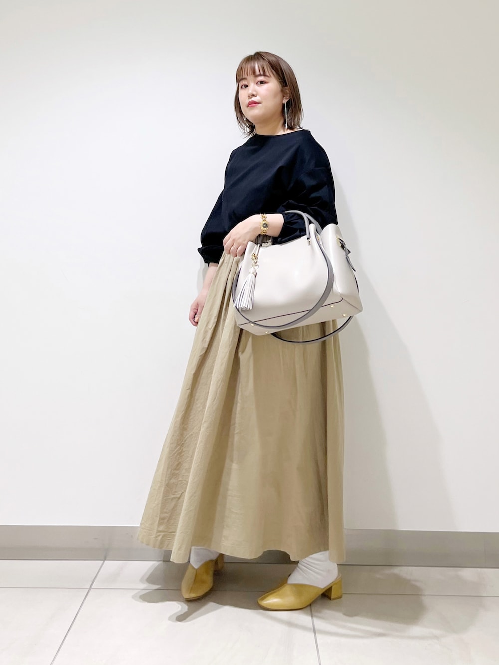 ブラック系のTシャツ/カットソー、ベージュ系のスカート、グレー系のトートバッグを着用したレディースの春コーディネートの2枚目の写真