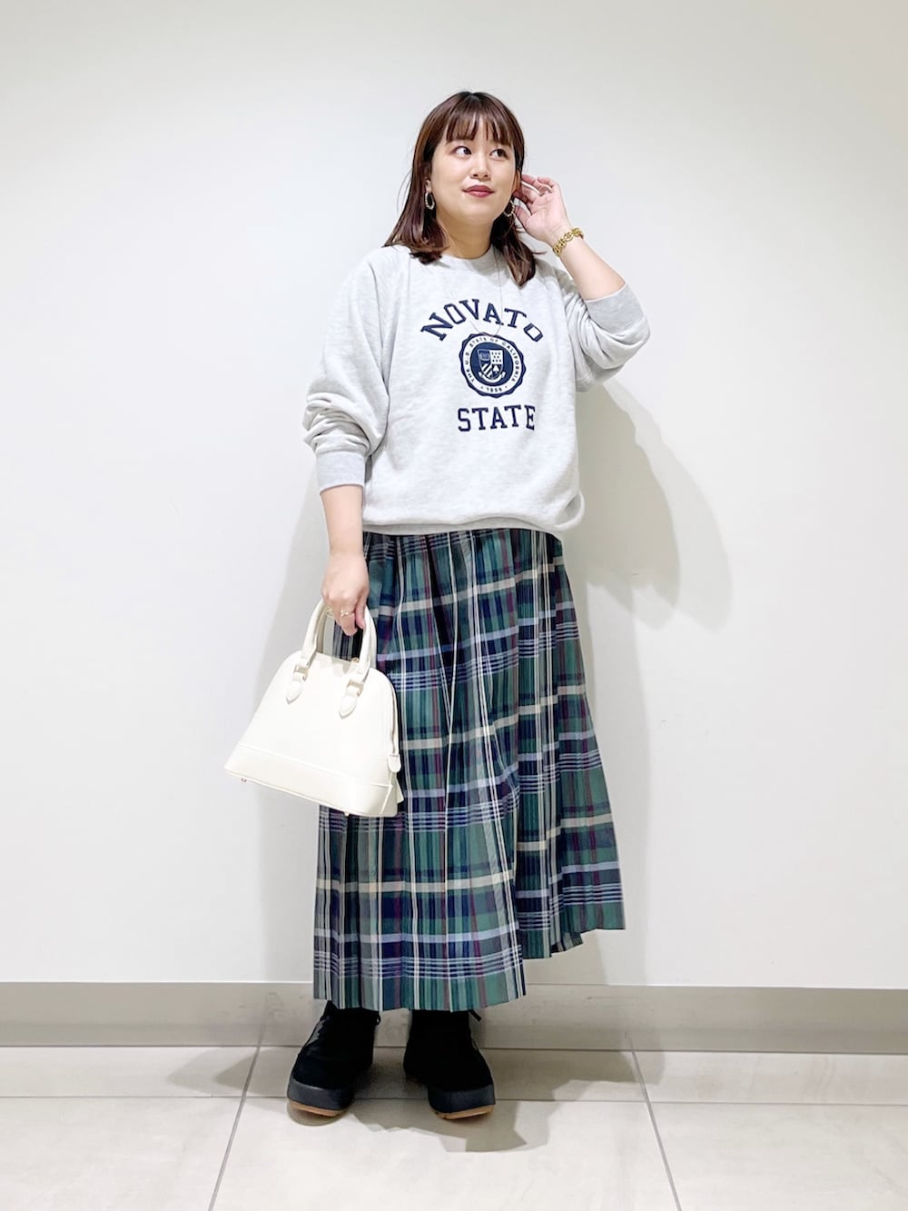 グリーン系のスカート、グレー系のスウェット、ホワイト系のショルダーバッグを着用したレディースの冬コーディネートの9枚目の写真