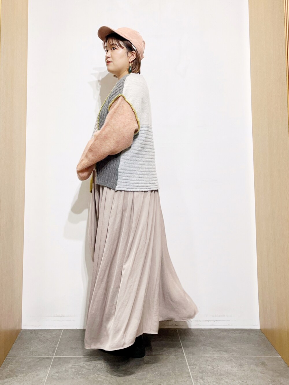 イエロー系のニット/セーター、グレー系のワンピース、ブラック系のブーツを着用したレディースの秋コーディネートの3枚目の写真