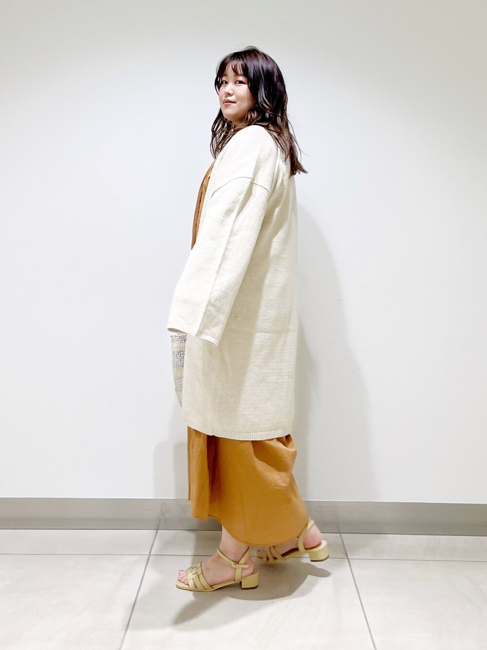 ブラウン系のワンピース、ホワイト系のカーディガン/ボレロ、ホワイト系のハンドバッグを着用したレディースの春コーディネートの3枚目の写真