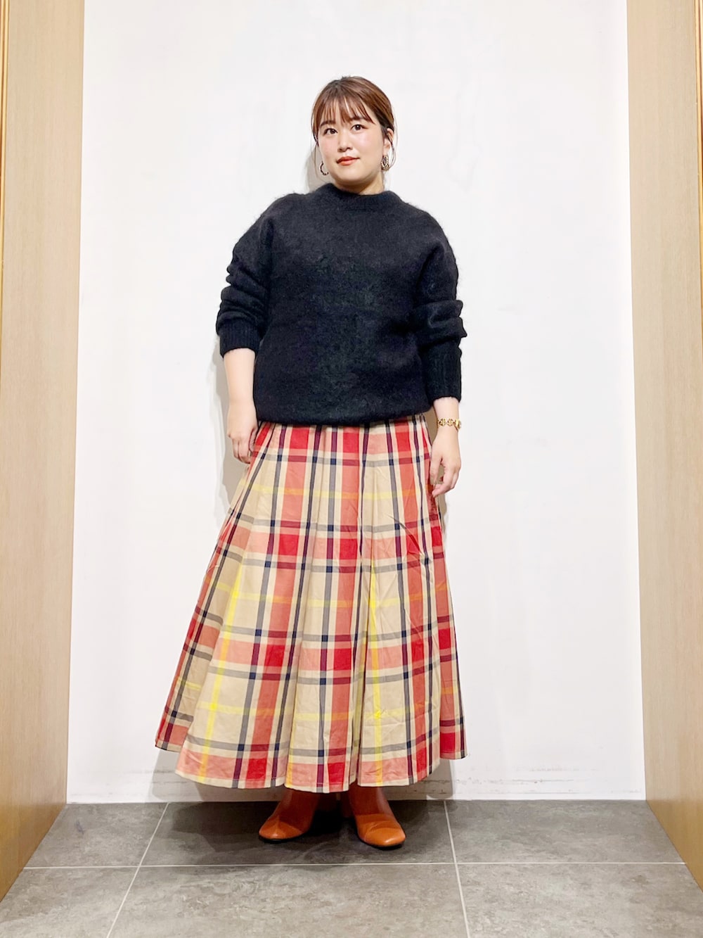 ブラック系のニット/セーター、ベージュ系のスカート、ピンク系のブーツを着用したレディースの秋コーディネートの2枚目の写真