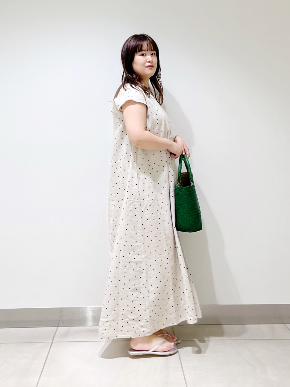 ベージュ系のワンピース、グリーン系のハンドバッグ、シルバー系のサンダルを着用したレディースの春コーディネートの6枚目の写真