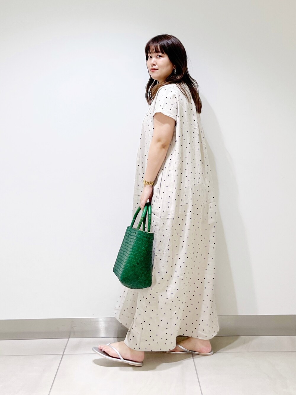 ベージュ系のワンピース、グリーン系のハンドバッグ、シルバー系のサンダルを着用したレディースの春コーディネートの7枚目の写真