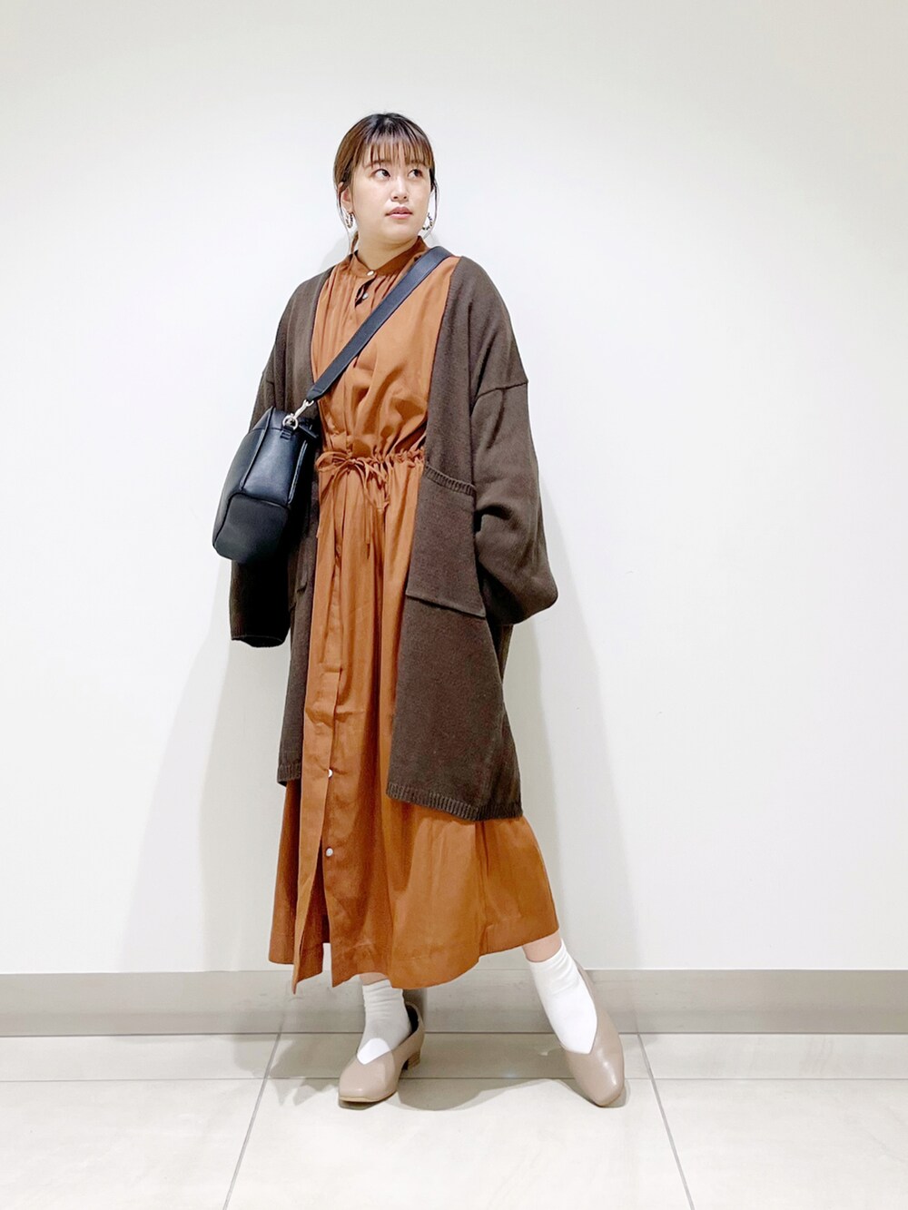 ブラウン系のカーディガン/ボレロ、イエロー系のワンピース、ブラック系のショルダーバッグを着用したレディースの秋コーディネートの2枚目の写真