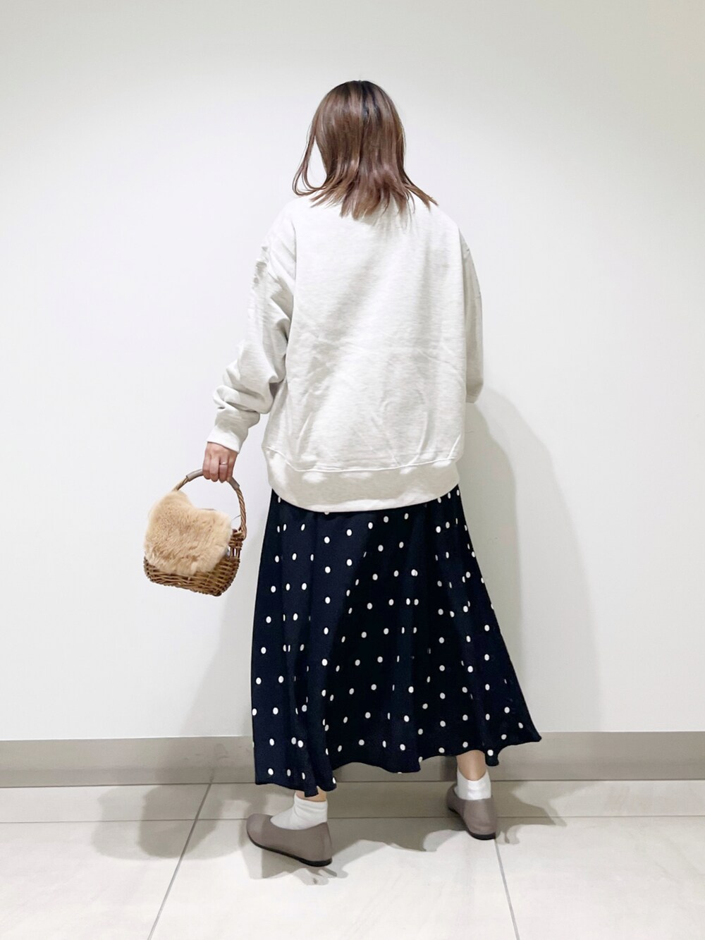 グレー系のスウェット、ベージュ系のかごバッグ、ブラック系のスカートを着用したレディースの秋コーディネートの5枚目の写真