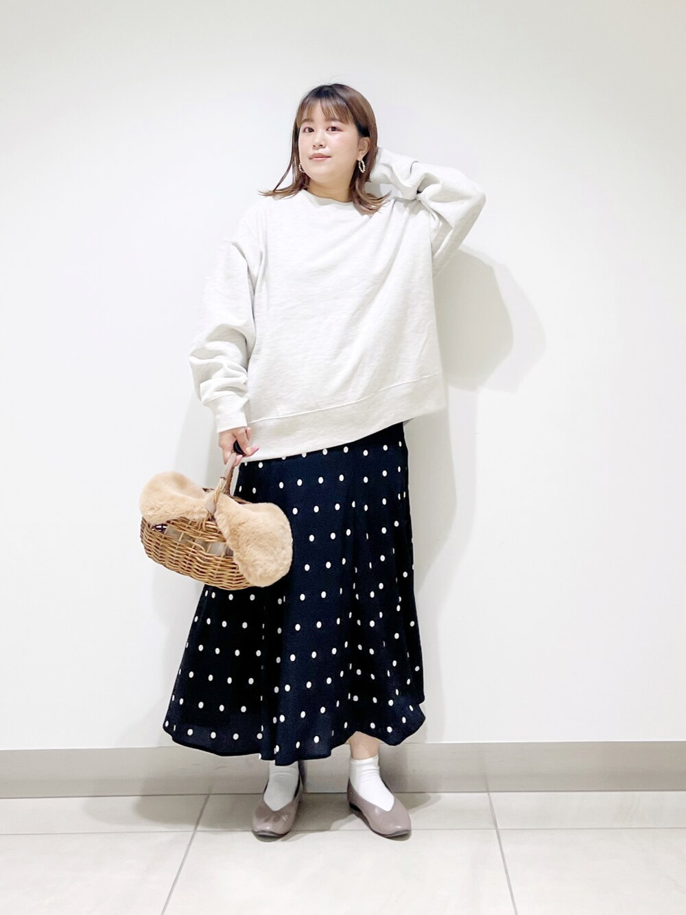 グレー系のスウェット、ベージュ系のかごバッグ、ブラック系のスカートを着用したレディースの秋コーディネートの4枚目の写真