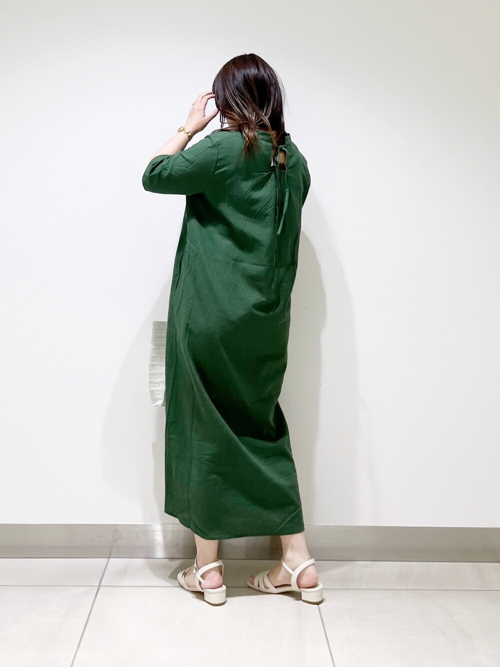 グリーン系のワンピース、ホワイト系のバッグ、ホワイト系のサンダルを着用したレディースの春コーディネートの3枚目の写真