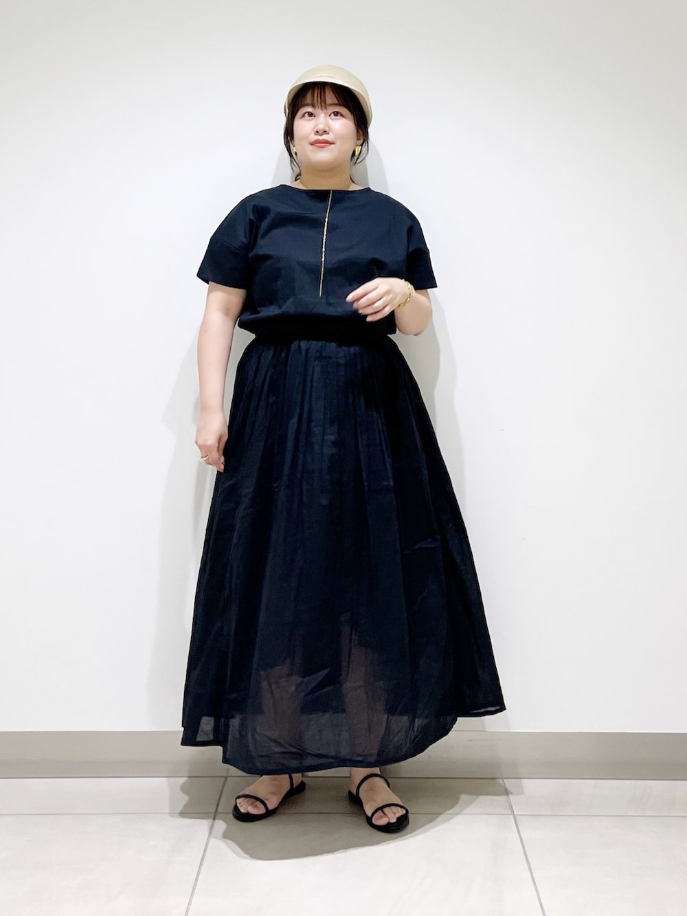 ブラック系のワンピース、ブラック系のサンダル、ベージュ系のキャスケットを着用したレディースの夏コーディネートの4枚目の写真