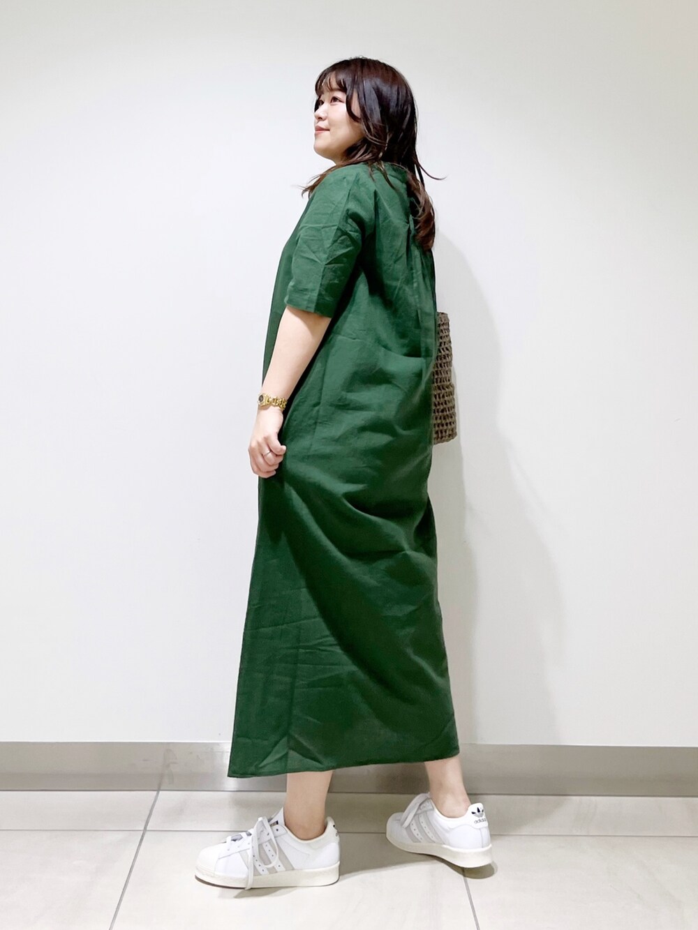 グリーン系のワンピース、グレー系のかごバッグ、ホワイト系のスニーカーを着用したレディースの夏コーディネートの7枚目の写真