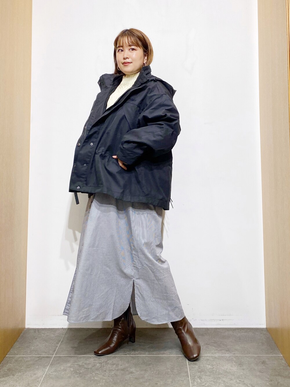 ブラック系のその他アウター、ホワイト系のワンピース、ブラウン系のブーツを着用したレディースの秋コーディネートの2枚目の写真