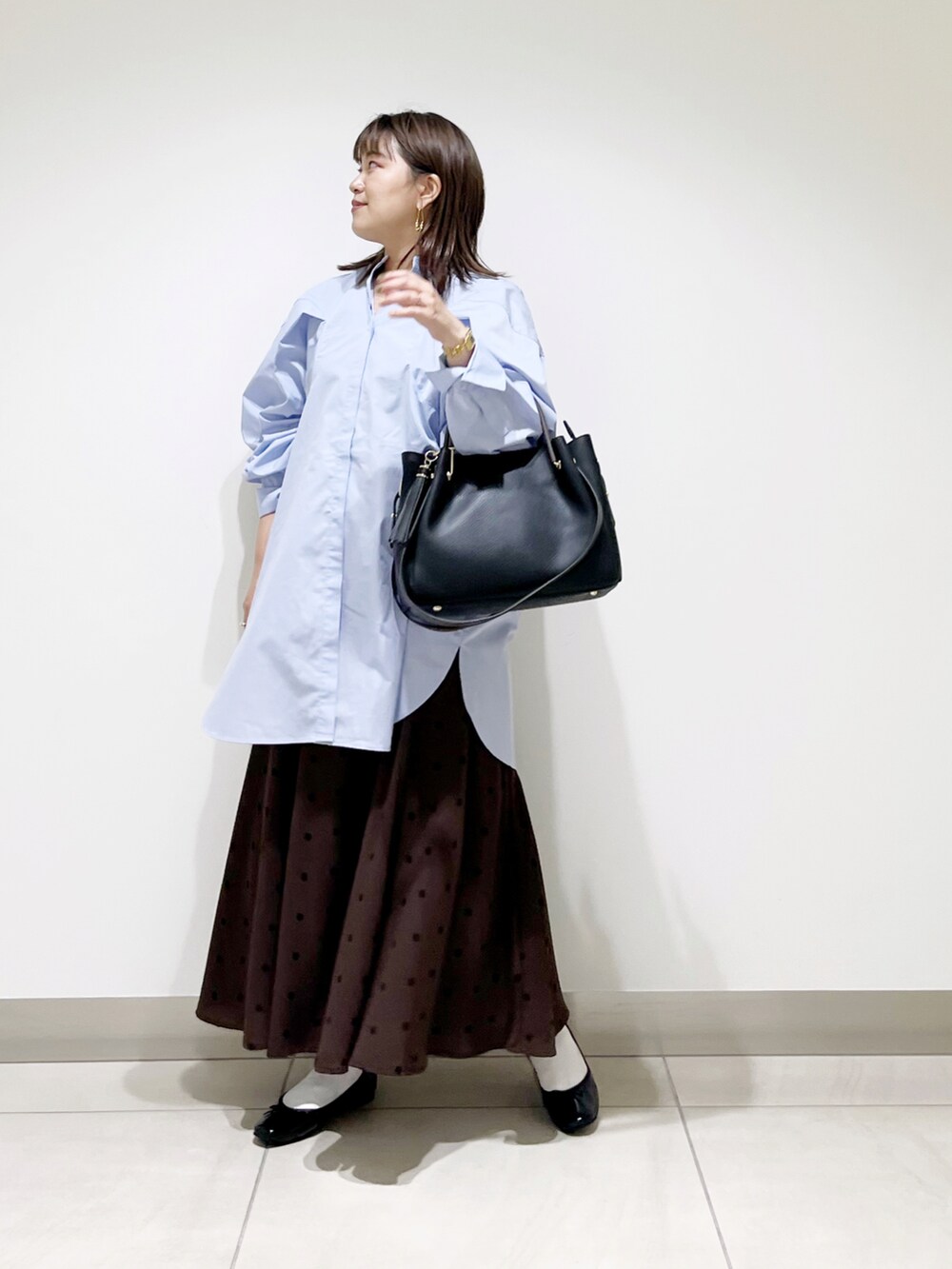 パープル系のワンピース、ブラック系のトートバッグ、ブラウン系のスカートを着用したレディースの秋コーディネートの5枚目の写真
