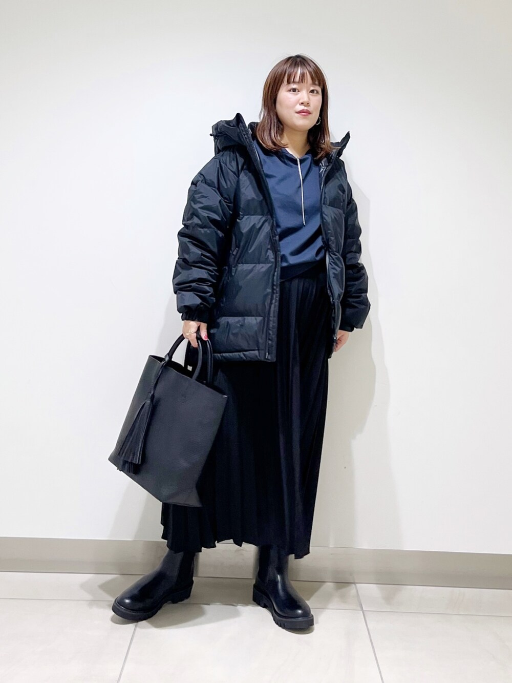 ブラック系のダウンジャケット/コート、ブルー系のTシャツ/カットソー、ブラック系のスカートを着用したレディースの秋コーディネートの2枚目の写真