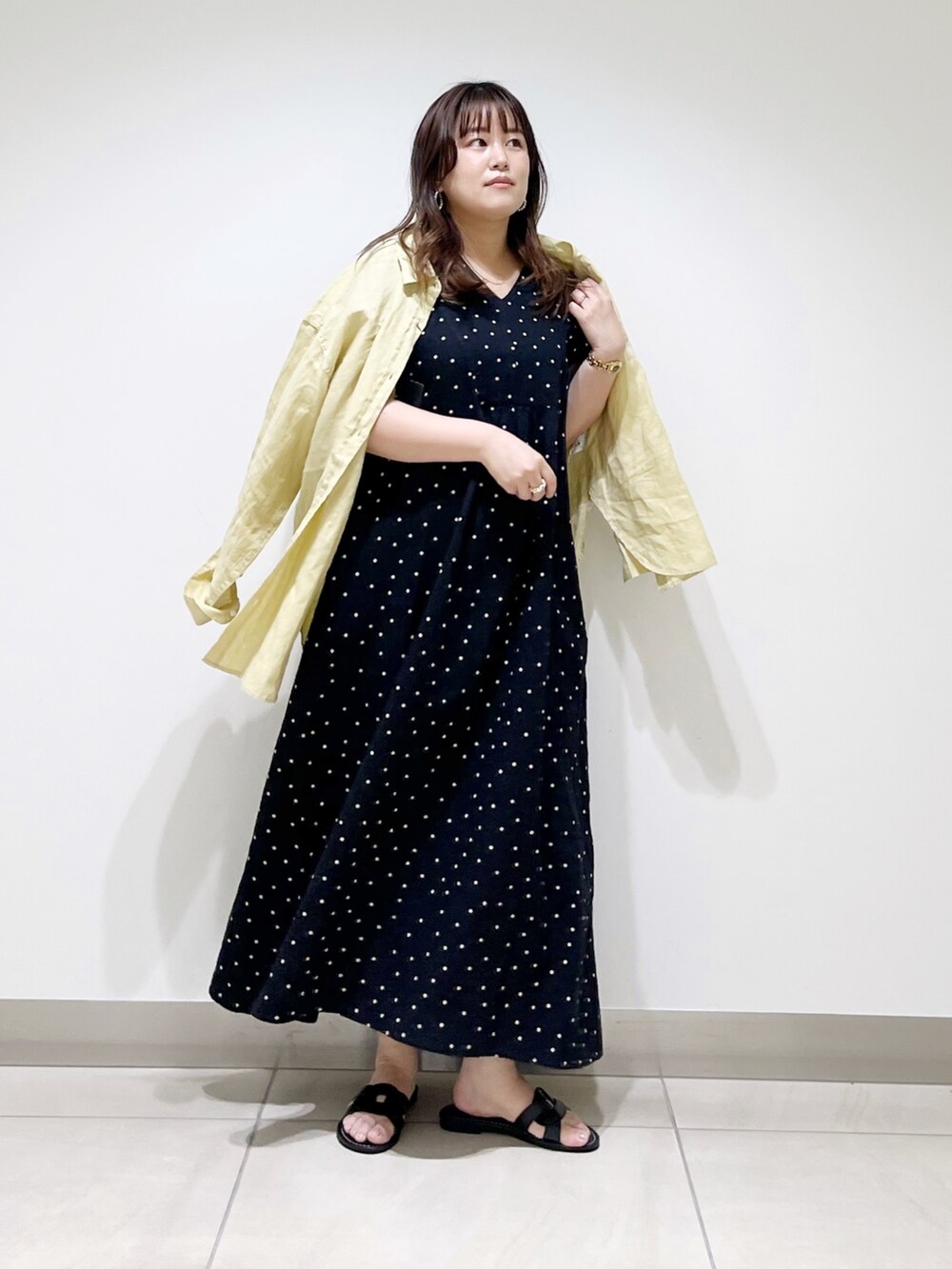 ブラック系のワンピース、イエロー系のシャツ/ブラウス、ブラック系のサンダルを着用したレディースの春コーディネートの2枚目の写真